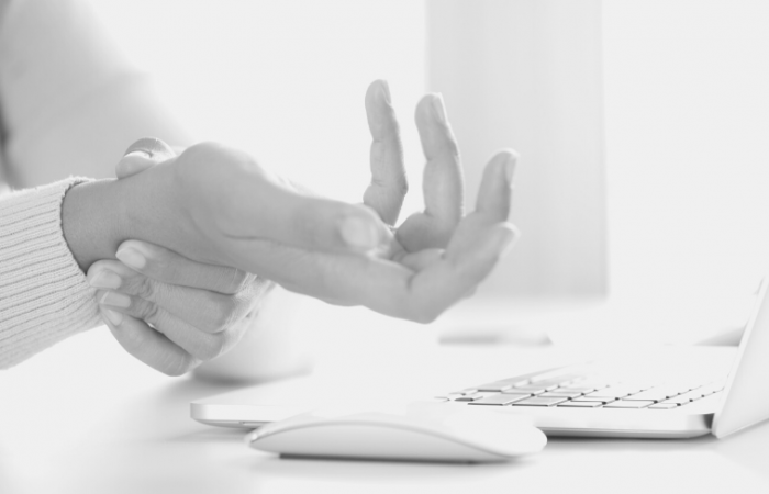 woman holding her wrist in pain at her computer